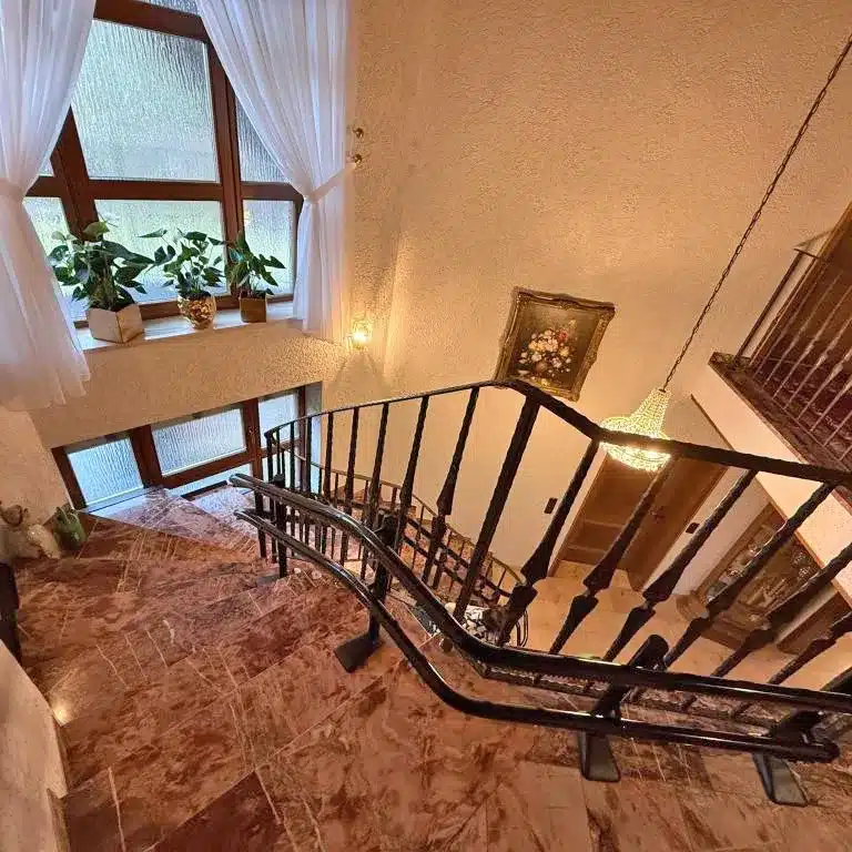 Blick von oben auf die Treppe aus Stein mit schwarzer Schiene für den Lift