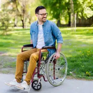 Lachender Mann sitzt im Rollstuhl im Park