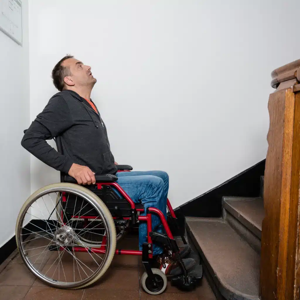 Mann im Rollstuhl blickt die Treppe hinauf