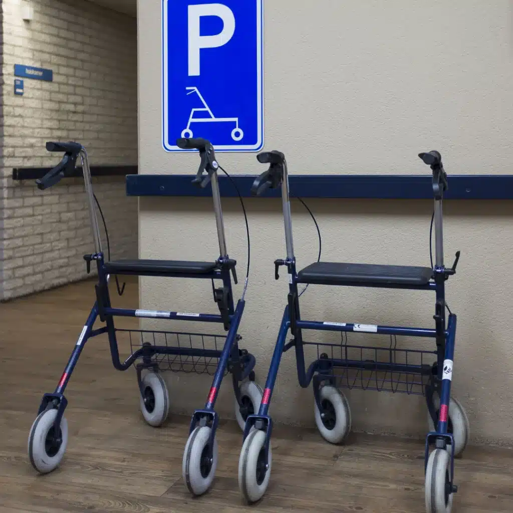 Zwei Rollatoren stehen im Innenraum vor Schild mit Rollator-Parkplatz