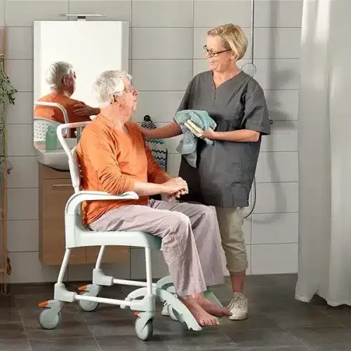 Pflegerin wäscht Senior auf einem Duschstuhl